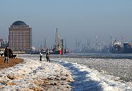 11_22735 Spaziergnger geniessen die Wintersonne am Elbstrand in Hamburg Neumhlen; das Elbufer ist mit Eis bedeckt. Im Hintergrund das ehemalige Khlhaus das zur Seniorenresidenz umgebaut wurde sowie der  Museumshafen von Oevelgoenne. www.fotograf-hamburg.de