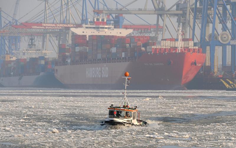 Winter in Hamburg - Barkasse im Treibeis auf der Elbe. 198_5372 Eine Barkasse berquert die Elbe durch den dichten Eisgang des Flusses. Im Hintergrund der Containerfrachter RIO DE JANEIRO der Reederei Hamburg Sd. Das 2008 gebaute Containerschiff kann 5900 TEU / Standartcontainer an Bord nehmen. Das 286 m lange Schiff kann bei einem max. Tiefgang von 13,5 m eine Geschwindigkeit von 23,0 kn erreichen.