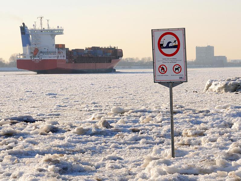 Hamburg-Fotos vom Winter - Eis auf der Elbe, Frachter. 208_5784 Zwischen dem Eis steht am Elbstrand ein Warnschild, das auf Wellenschlag und Sog sowie auf die Gefahr des Ertrinkens hinweist. Der Container Feeder NAVI BALTIC hat den Hamburger Hafen verlassen und fhrt elbabwrts durch das Treibeis. 