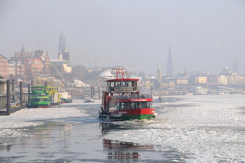 Fotografien vom Winter in der Hansestadt Hamburg - Panorama. 211_5327 Die Elbfhre REEPERBAHN bahnt sich ihren Weg durch das dichte Treibeis auf der Elbe - im Hintergrund das typische Hamburg Panorama mit den unterschiedlichen Kirchtrmen im Dunst des Winternachmittags. 