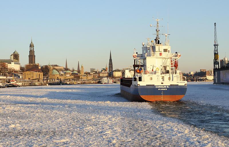 Panorama von Hamburg im Winter - Michel + Landungsbrcken. 213_5837 Die Elbe ist vor den St. Pauli Landungsbrcken dicht mit Treibeis bedeckt. Der Containerfeeder CAROLIN G. bahnt sich den Weg durch die Eisschollen, um seinen Liegeplatz im Hamburger Hafen zu erreichen. Im Hintergrund das Hamburger Panorama mit den Sandsteingebuden der Landungsbrcken, dem Kuppelgebude des Alten Elbtunnels und den Kirchtrmen von vier der fnf Hamburger Hauptkirchen. 