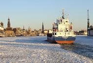 213_5837 Die Elbe ist vor den St. Pauli Landungsbrcken dicht mit Treibeis bedeckt. Der Containerfeeder CAROLIN G. bahnt sich den Weg durch die Eisschollen, um seinen Liegeplatz im Hamburger Hafen zu erreichen. Im Hintergrund das Hamburger Panorama mit den Sandsteingebuden der Landungsbrcken, dem Kuppelgebude des Alten Elbtunnels und den Kirchtrmen von vier der fnf Hamburger Hauptkirchen.