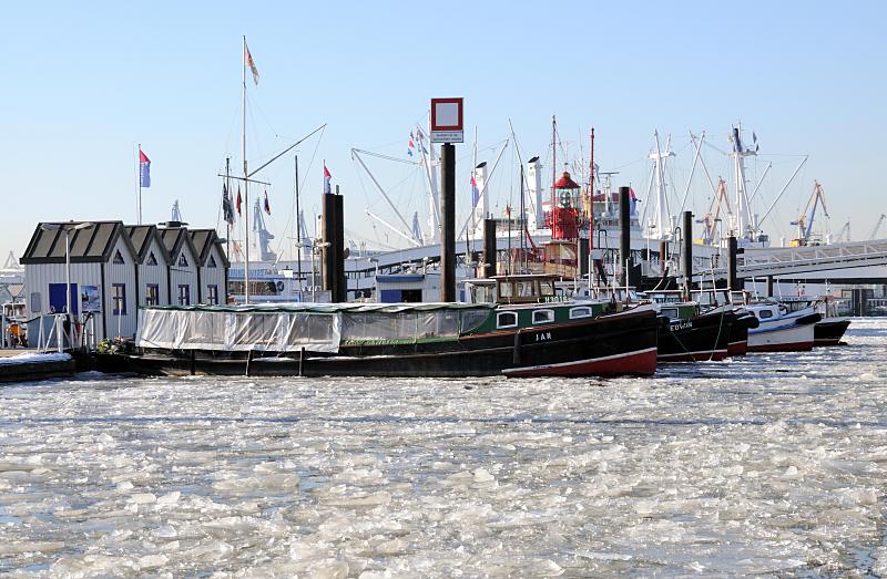 Winter in Hamburg - Barkassen im vereisten Niederhafen / Vorsetzen. 217_5629 Barkassen der Hafenrundfahrt liegen vertut im Eis des Hafens am Anleger Hhe Vorsetzten. Das dichte Treibeis der Elbe machen die Touristiktouren durch den Hafen fast unmglich. Im Hintergrund das Feuerschiff im beim City Sportboothafen und die berseebrcke mit Teilen der Aufbauten vom Museumsschiff Cap San Diego.