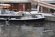 222_4879 Das Wasser im Hamburger Traditionsschiffhafen ist mit Eis bedeckt - am Ponton des Sandtorhafens liegt der historische Schlepper FAIRPLAY VIII, das Heck des Arbeitschiffs ist mit Schnee bedeckt; an der Seite steht der Heimathafen Hamburg.