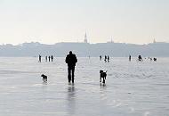 233_5484 Obwohl die zugefrorene Alster noch nicht offiziell zum Betreten freigeben ist, gehen die Hamburger auf dem Alstereis spazieren und geniessen den aussergewhnlichen Ausblick. Sie fahren sogar Fahrrad oder nehmen Ihre Hunde mit aufs Eis. Im Hintergrund der Kirchturm der  Hl. Dreieinigkeitskirche in Hamburg - St. Georg.