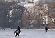 238_5528 Schlittschuhlaufen auf der zugefrorenen Hamburger Aussenalster - eine Mutter schiebt beim Eislauf ihren Kinderwagen. Am Ufer der Alster das Gebude der Amerikanischen Botschaft mit der Flagge auf dem Dach des weissen Hauses und lks. der Kuppelturm des Hamburger Michels. 