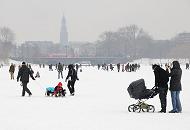 246_6117 Die Hamburgerinnen und Hamburger genieen mit ihren Kinder das Alstereisvergngen auf der Auenalster. Sie ziehen ihre Sprlinge auf einem Schlitten ber das Eis oder schieben ihren Kinderwagen ber die Alster. Im Hintergrund der Michelturm - ber die Lombardsbrcke fhrt ein Zug.