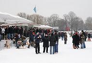 247_6130 Auf dem Alsterponton, an dem normalerweise die Alsterschiffe anlegen, stehen die Hamburger Alsterbesucher Schlange, um an einem der Verkaufsstnde heien Glhwein oder eine Bratwurst zu kaufen. Andere stehen im Schneetreiben auf dem Eis der Alster und genieen die Hamburger Winteratmosphre. 