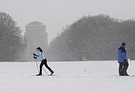 263_5059 Die groe Wiese im Zentrum des Stadtparks ist zugeschneit. Eine Skilangluferin fhrt durch den winterlichen Stadtpark, whrend ein Spaziergnger dick verpackt durch das Schneetreiben stapft.  Im Hintergrund das Hamburger Planetariums. Der ehemalige Wasserturm wird seit 1930 als Planetarium genutzt.