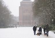 264_5083 Familien gehen im Schnee des Hamburger Stadtparks spazieren - Vter ziehen ihre Sprsslinge auf dem Schlitten oder tragen sie Huckepack, eine Mutter schiebt ihren Kinderwagen durch den Schnee auf dem Weg zum Planetarium. Der Schriftzug steht in goldfarbenen Buchstaben an der Fasse des 78m hohen Gebudes. www.fotos-hamburg.de