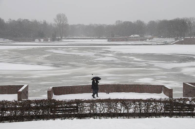 Hamburger Winter - Grauer Wintertag am Stadtparks, Hamburger Stadtpark. 268_5042 An einem grauen Wintertag geht ein Paar am Stadtparksee spazieren - sie schützen sich mti einem Schirm gegen den Schneefall. Auf dem fast zugefrorenen See sitzen Möwen auf dem dünnen Eis. Im Hintergrund das Freibad Stadtparksee
