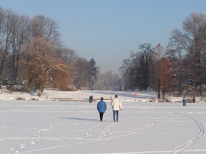 Hamburger Winterimpressionen - Spaziergang im Schnee. 273_1010017 Bei strahlendem Winterwetter sind die Hamburger auch gerne im Stadtpark. ber den zugefrorenen Stadtparksee geht ein Paar Richtung Bootsanleger, der sich jetzt im Bereich des zerstrten Parkcafs befindet.