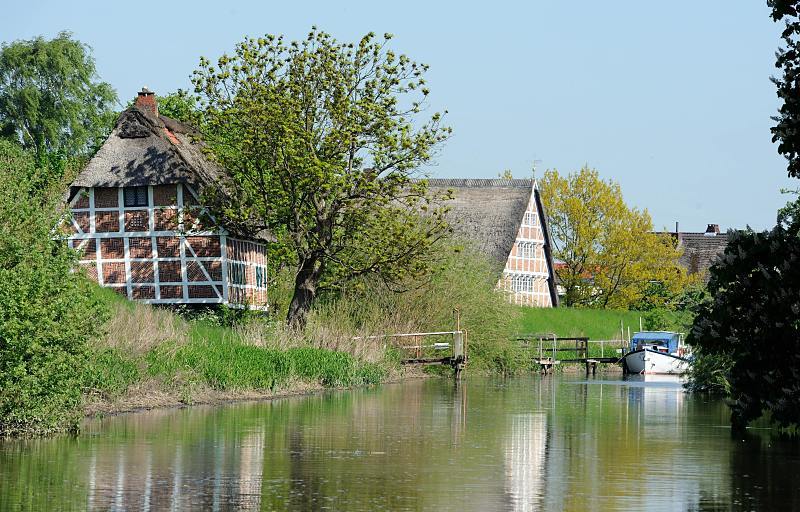 024_4098 Dicht stehen die Fachwerkhäuser am Ufer der LÜHE. Das Alte Land ist mit ca. 14 3000 Hektar Baumobst der Obstkorb der Nation. Der Name Altes Land hat nichts mit 'alt' zu tun, sondern weist auf die Besiedlungsgeschichte hin. Auf Plattdeutsch heißt das Gebiet Olland (hochd. 'Altland'). Dieser Name geht auf die Kolonisierung durch niederländische Kolonisten zurück. Als Begründer des Alten Landes gilt Priester Hendrik aus Jacobswoude, dessen Wirken urkundlich belegt ist. Fotos aus dem Alten Land - Frühling am Ufer der LÜHE. Historische Fachwerkhäuser - Reetdachhäuser am Deich.
