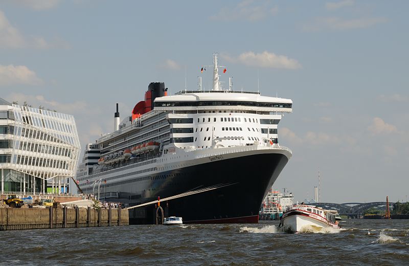 Luxusliner Queen Mary 2 QM2 am Hamburger Kreuzfahrtterminal - Hafenbarkassen  02_4353 Die Queen Mary 2 am Kreuzfahrtterminal im Hamburger Hafen. Viele Hamburger und Hamburg-Touristen nutzen die Gelegenheit und machen mit einer der vielen Hafenbarkassen eine Hafenrundfahrt. Auf dieser Hafentour fahren die Barkassen auch nahe an die Queen Mary heran.  Die R.M.S. (Royal Mail Ship)  Queen Mary 2 (QM2) ist mit 148.528 BRZ eines der grten Passagierschiff der Welt. Das britische Kreuzfahrtschiff  hat eine Lnge von 345 m und eine Breite von 45 m. Der Luxusliner bietet in 1310 Kabinen bis zu 2.620 Passagieren Platz und hat eine Besatzung von 1.253 Personen. Die Queen Mary 2 hat fnf Swimmingpools, einen Ballsaal, Golfanlage, Wintergarten, Sportzentrum, mit ber 8.000 Bchern die grte Bibliothek auf See, den grten ffentlichen Saal (Restaurant Britannia), der ber zwei Decks und die gesamte Schiffsbreite geht, acht weitere Restaurants, Fitness-Center, Planetarium, Kino, Theater.  www.fotograf-hamburg.de