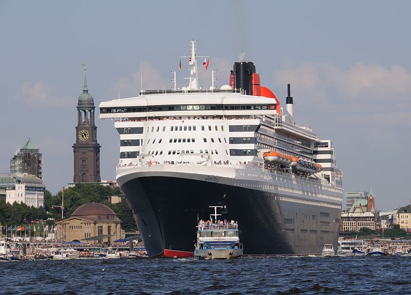 Die Queen Mary 2 verlsst den Hamburger Hafen - Fahrt auf der Elbe, St. Michaeliskirche. 07_4382 Die Queen Mary 2 auf der Elbe vor den St. Pauli Landungsbrcken; lks. die Kuppel vom Eingang des St. Pauli Elbtunnels und dahinter der hohe Kirchturm vom Hamburger Michel - echts die Gustav-Adolf-Kirche. Viele Barkassen, Fahrgastschiff und Motorboote begleiten den Luxusliner bei  seiner Fahrt auf der Elbe - an den Landungsbrcken stehen die Schaulustigen dicht gedrng. www.fotograf- hamburg.de