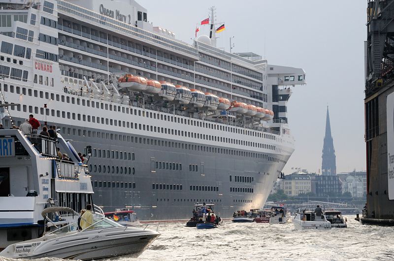 Schiff-Fotos aus dem Hamburger Hafen. Empfang der Queen Mary 2 in Hamburg - Sportboote, Motoryachten; St. Nikolaikirche. Hamburger Hafenfotos -  Fotograf Christoph U. Bellin. 20_4702 Bei ihrer Einfahrt in den Hamburger Hafen wird das riesige Passagierschiff von vielen Sportbooten und Hafenrundfahrtschiffe zum Liegeplatz am Cruise Center begleitet. Im Hintergrund der Kirchturm der St. Nikolai-Kirche, deren Kriegsruine als Mahnmal die Innenstadt Hamburgs berragt. www.fotograf- hamburg.de