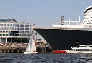 24_4828 Die Queen Mary 2 hat am Chicago-Kai des Hamburger Kreuzfahrtterminals festgemacht - Schaulustige sitzen auf der Terrasse und bewundern das grosse Schiff. Ein Segelboot kreuzt vor dem Bug des Luxusliners, ein Fahrgastschiff mit Touristen an Bord fahren an der Lngsseite des Schiffs entlang.  www.fotograf- hamburg.de