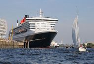 25_4838 Die Queen Mary 2 hat am Chicago-Kai des Hamburger Kreuzfahrtterminals festgemacht - ein Segelboot kreuzt vor dem Bug des Luxusliners. Im Hintergrund die Elbbrcken ber die Norderelbe, dahinter der Schornstein vom Kraftwerk Tiefstack.  www.fotograf- hamburg.de