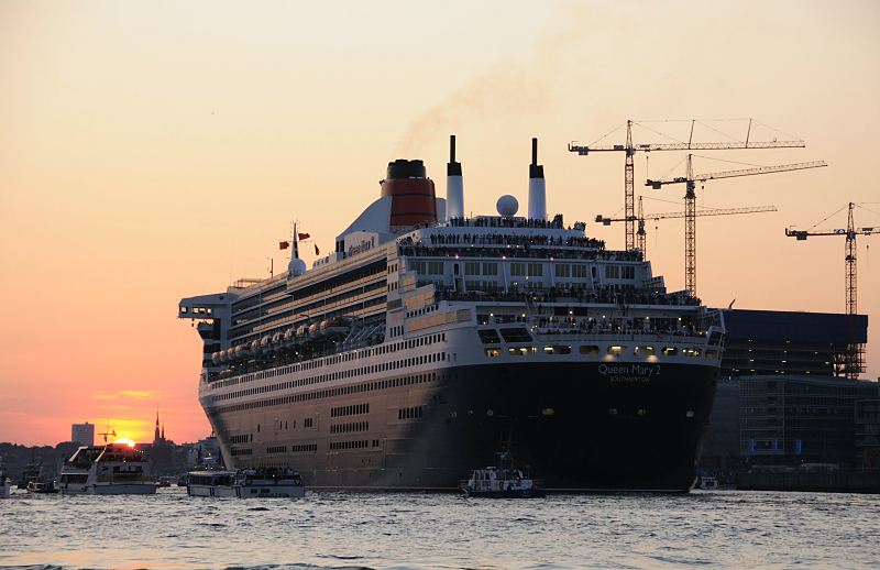 Schiffsfots aus Hamburg. Die Queen Mary 2 verlsst Hamburg - Sonnenuntergang ber Hamburg St. Pauli. Hamburger Hafenfotografie Christoph U. Bellin. 27_4950 Die Queen Mary 2 hat am Cruise Center abgelegt und fhrt an der Baustelle der Hamburger Elbphilharmonie vorbei. Die Sonne versinkt gerade hinter den Husern von Hamburg St. Pauli - Fahrgastschiffe und Motorboote warten darauf, das Kreuzfahrtschiff beim Verlassen des Hamburger Hafens zu begleiten und zu verabschieden. www.fotograf- hamburg.de