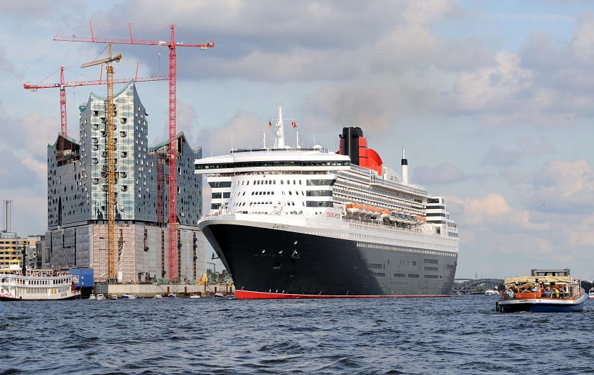 8552 Das Kreuzfahrtschiff Queen Mary luft aus dem Hamburger Hafen aus - im Hintergrund die Baustelle der Elbphilharmonie mit hohen Baukrnen. Ausflugsschiffe mit Touristen an Bord begleiten das Passagierschiff beim Auslaufen aus dem Hamburger Hafen.