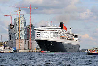 8550 Die Queen Mary verlsst den Hamburger Hafen - das Kreuzfahrtschiff hat vom Kreuzfahrtterminal Hafencity abgelegt und fhrt Hhe Elbphilharmonie. Touristen an Bord einer Barkasse der Hamburger Hafenrundfahrt beobachten das Auslaufen des grossen Kreuzfahrtschiffs