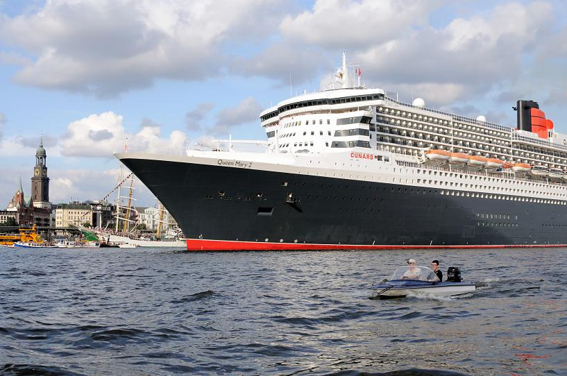 8565 Bug der Queen Mary 2 - im Hintergrund die St. Michaeliskirche, dem Wahrzeichen der Hansestadt Hamburg. Kleines Motorboot mit Aussenbordmotor in Fahrt auf der Elbe.