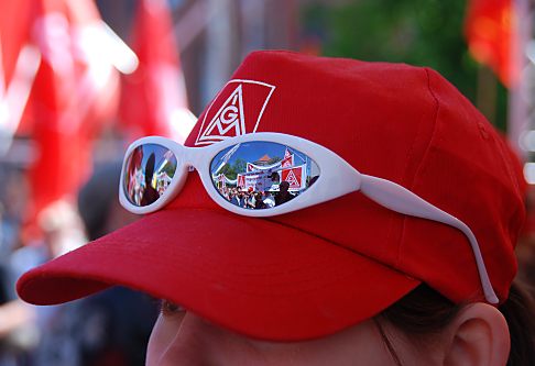 011_15543 - eine rote Mtze mit dem IGM Aufdruck, dem Logo der IG Metall; in der Sonnenbrille spiegeln sich Transparente und Teilnehmer der Maikundgebung. 