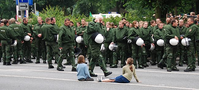 011_15688 - zwei Mdchen sitzen auf der Strasse und beobachten, wie die Polizei in Kampfanzgen sich sammelt. 