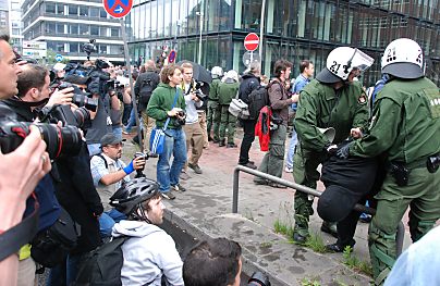 011_15699 - die anwesende Presse fotografiert den ber ein Metallbgel abgelegten Demonstranten; im Hintergrund scheints noch mehr Gerangel zu geben.