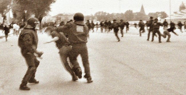 011_15700 - Heiligengeistfeld nach der Demonstration: ein Polizei - Mannschaftswagen hlt, ca. acht Polizisten mit Helm und Kampfanzug strzen sich mit Geschrei auf schwarz gekleidete Jugendliche, die plaudernd ber den Platz gehen. Immer zwei Vertreter der Staatsgewalt prgeln  kurz auf ihr Opfer ein, bis er / sie am Boden liegt. Nach zwei, drei Minuten sammeln sich die recht jung aussehenden Polizisten wieder um ihren Gruppenfhrer; sie werden mit einem GUT GEMACHT gelobt und steigen wieder in ihren Bus.  (die ganze Aktion erweckte den Eindruck, als wenn sie Teil des Ausbildungsprogramms fr Lehrlingspolizisten gewesen ist.)