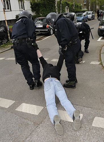 011_17490 - ein Demonstrant, der an einer Strassenblockade teilgenommen hat wird von zwei Polizisten an den Armen ber die Strasse in eine Seitenstrasse geschleift, damit der Marsch der NPD weiter durch das Viertel gehen kann. 