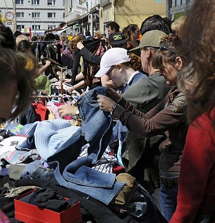 011_17493 - Auf den aufgestellten Tapeziertischen bieten die Anwohner und Anwohner die unterschiedlichsten Gegenstnde auf dem Trdelmarkt zum Verkauf an. Besonders beliebt ist es, ausrangierte Kleidung auf dem Flohmarkt zu verkaufen. Prfend werden alte Jeans oder Pullover in den Hnden gehalten, um das Aussehen und den Wert der angebotenen Ware abzuschtzen.