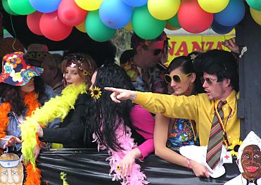 011_14213 - Elvis Presley mit Krawatte, Frauen mit Federboa und Blumenhut auf dem Musikwagen. 