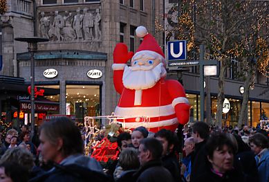 11_15255 - Bein Weihnachtsfigur aufblasbar aus Plastik winkt in der Menschenmenge in der Mnckebergstrasse.
