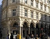 11_18978 Blick ber den Gustav-Mahler-Platz zum Sulengang der Hamburger Colonnaden. Passanten schlendern ber den Platz oder sitzen in der Sonne. An der Strassenecke stehen zwei gelbe Briefksten mit Posthorn. Das historische Etagenhaus war ca. 1880 als Wohngebude errichtet, jetzt befinden sich zumeist dort Bros o..   www.bildarchiv-hamburg.de